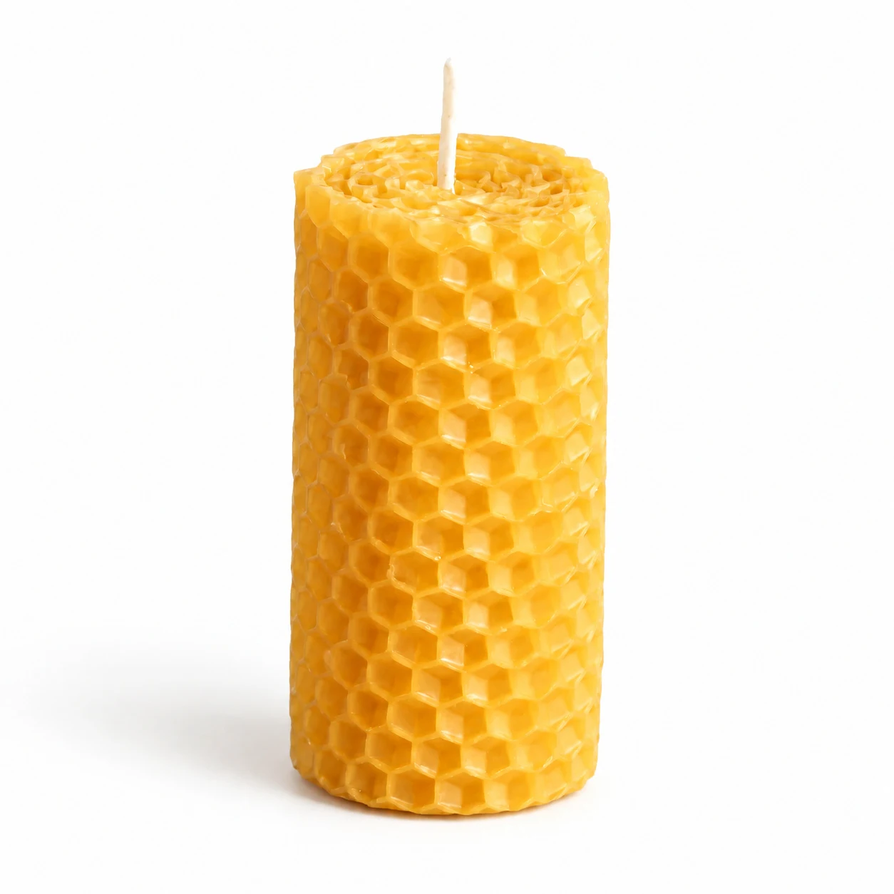 A single honeycomb beeswax candle with its wick, upright against a plain light background