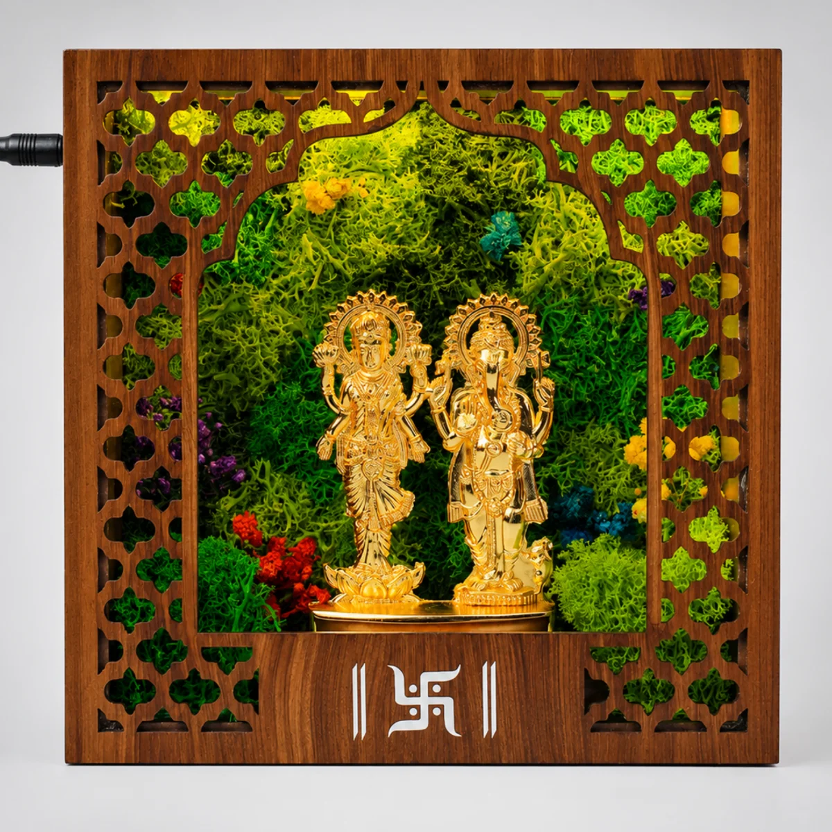 Straight-on view of the lit mandir, with metal Laxmi-Ganesh idols and preserved moss behind the jali frame