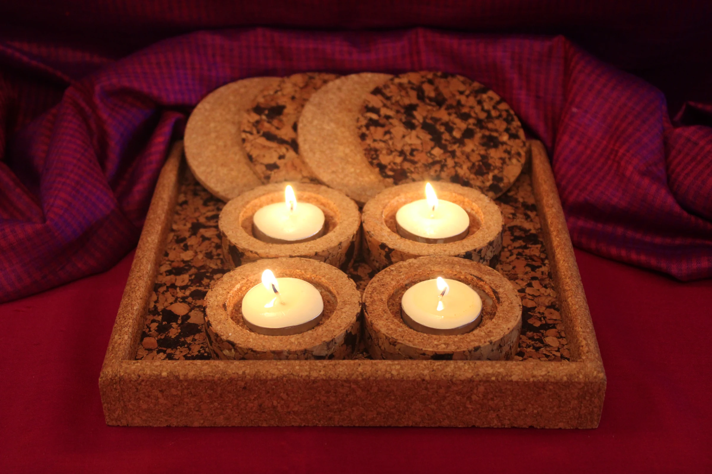 SC801 cork tray set with four lit cork diyas and coasters on a burgundy textile